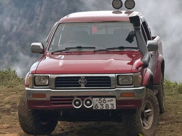 Red Toyota Hilux on a misty hilltop